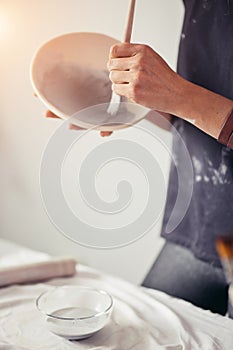 Woman painting clay pot with senior potter at workshop