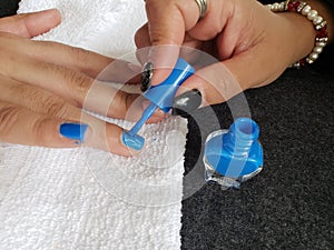 woman painting the fingernails of another woman with blue nail polish photo