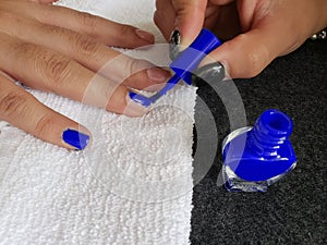 woman painting the fingernails of another woman with dark blue nail polish photo