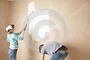 Woman Painting And Man Bending In Unrenovated House