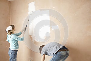 Woman Painting And Man Bending In Unrenovated House photo