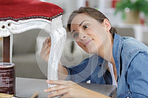 Woman painting renewing chair at home