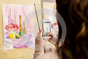 Woman with painting on smartphone at art school