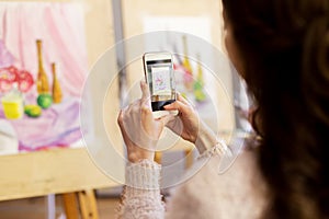 Woman with painting on smartphone at art school