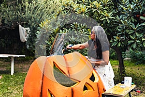 Woman painting the top part of a giant polystyrene pumpkin outdoors photo