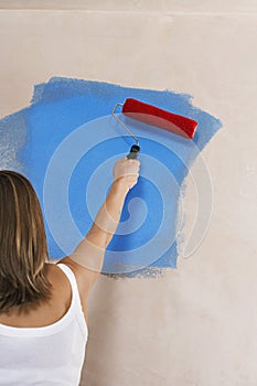 Woman Painting Wall Blue With Paint Roller