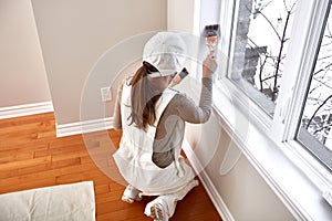 Woman painting window trim