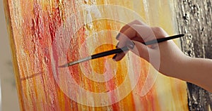 Woman paintress painting abstract picture using brush on canvas, hand closeup.