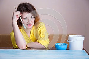 A woman paints boards, before her stand cans of paint