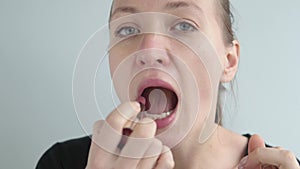 A woman paints her lips with light lipstick.