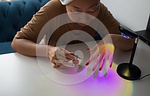 Woman paints her nails with red polish herself at home. Manicured red nails