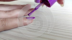 Woman paints nails with purple nail polish
