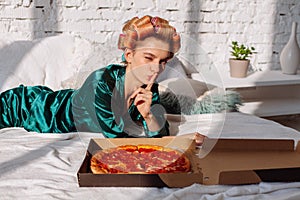 Woman in pajama with pizza in bedroom