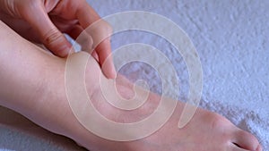 Woman palpates hand leg ankle hygroma in joint, foot closeup view.