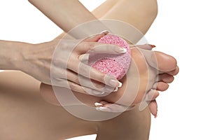 Woman pampring her foot with sponge on a white studio background