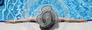 Woman in panama lying on edge of swimming pool top view