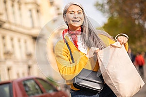 Woman with a papaer bag after shopping in a city street