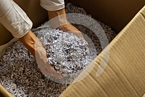 woman with paper packaging in hands inside cardboard box