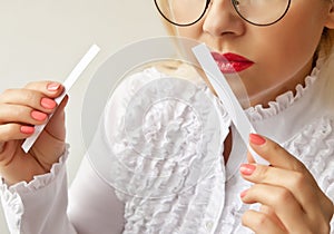 A woman with paper strips in her hands listens to the fragrance.