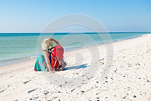 Woman in a pareo with backpack relaxes on the deserted beach