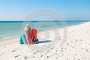 Woman in a pareo with backpack relaxes on the deserted beach