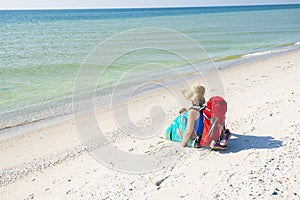 Woman in a pareo with backpack relaxes on the deserted beach