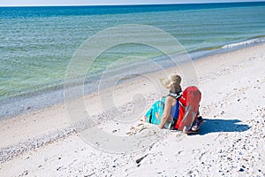 Woman in a pareo with backpack relaxes on the deserted beach