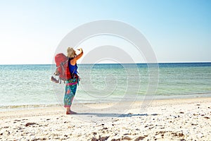 Woman in a pareo with backpack stands on the deserted beach