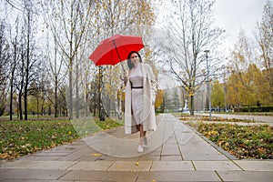 Woman in the park dancing under a red umbrella in the rain