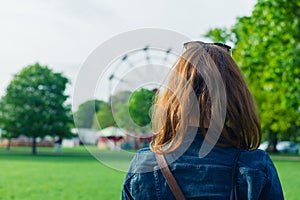 Woman in park looking at fun fair