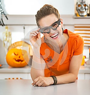 Woman in party bat glasses in the Halloween decorated kitchen