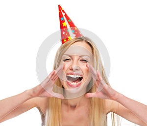 Woman in party cap shouting through megaphone shaped hands