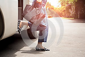 Woman passenger with black hand bag getting off the bus