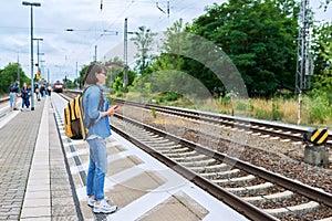 Woman passenger waiting for commuter train at station outdoor platform