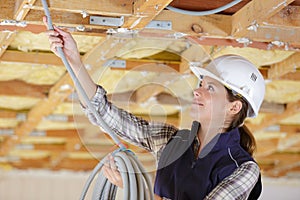 Woman passing cables overhead into roofspace