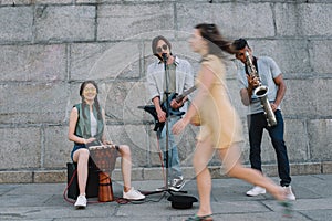 Woman passing by multiracial band of street musicians