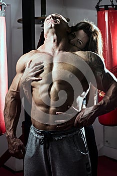 Woman passionately embraces muscular man in the gym