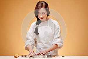 Woman pastry chef background cuts Christmas cookies with metal shapes.