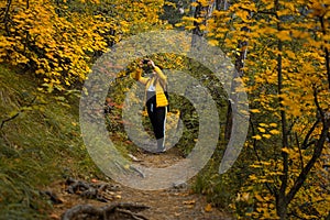 Woman path autumn forest. A young dark-haired woman in a yellow-black suit