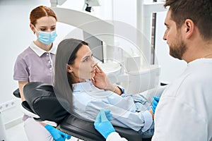 Woman patient complaining to dentist on dull and constant toothache