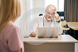 Woman patient consulting with male doctor in clinic office