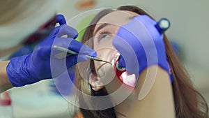 Woman patient at dental procedure. Dentist work with dental polymerization lamp