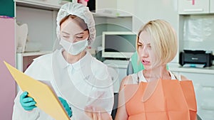 woman patient at dentist appointment, giving questions to female doctor, orthodontist consultation