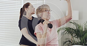 Woman patient, dumbbell exercise and physiotherapist for rehabilitation and physical therapy. Senior person with a
