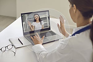 Woman patient greeting her doctor online from laptop screen during videocall on laptop