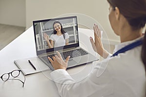 Woman patient greeting her doctor online from laptop screen during videocall on laptop photo