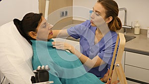 Woman patient having consultation in aesthetic clinic, showing to beautician what she want change in face