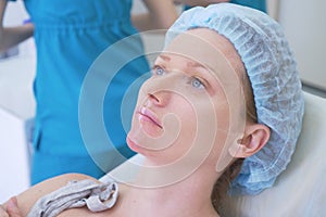 Woman patient in a hygienic hat expects the procedure in the doctor`s office. close-up. 4k