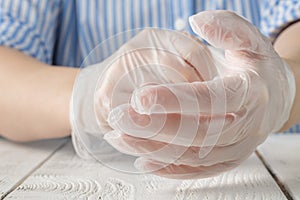 Woman patient in a medical mask puts on protective surgical sterile gloves on her arm, protection against coronovirus