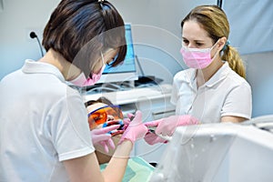 Woman patient with protective glasses and retractor for teeth whitening procedure